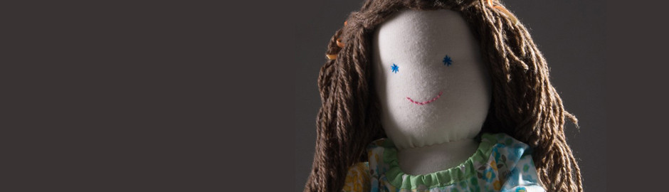 Face of a pale fabric doll with long brown hair