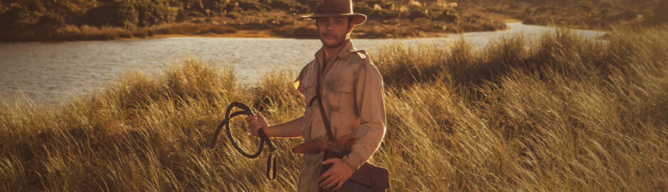 A young man in a tan uniform stands in a golden tussock landscape.