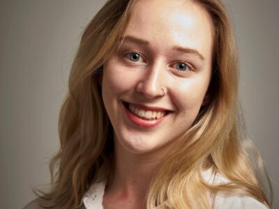 Anna Barker is smiling in front of a grey background